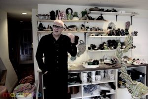 Sculptor Daniel Wiener stands in front of his shelves of artwork