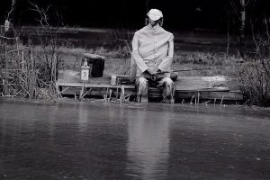 Black and White photograph of a man fishing at a dock