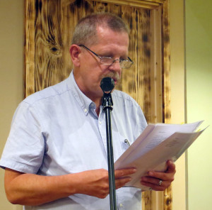 Poet activist Reuben Woolley reads poetry at a microphone.