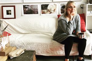 Artist Sue Wrbican on the sofa in her studio, from The Studio Visit website