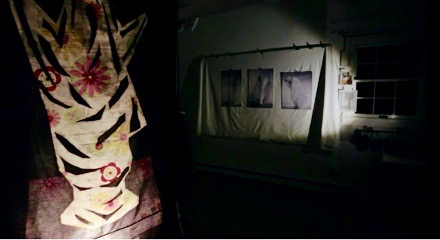 A batik artwork in a spotlight in a dark room
