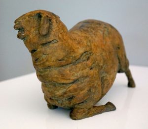 A bronze statue oof a kneeling sheep