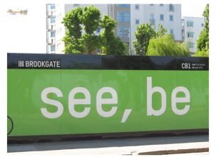 A bright green sign with the words "see, be"