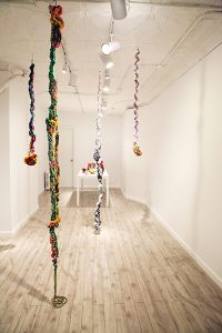 An installation of large, colorful wire and bead sculptures hanging from the ceiling