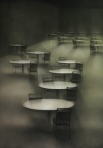 A painting of a number of empty tables shrouded in fog