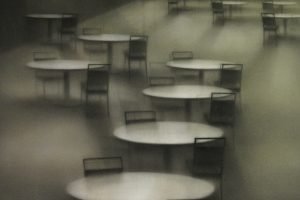 A painting of a number of empty tables shrouded in fog