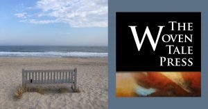 The view of a Hamptons beach, with a bench on the sand overlooking the ocean