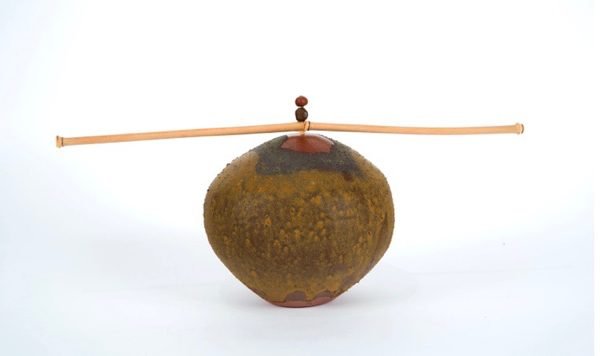 A sculpture of a bamboo stick balancing on top of a round object