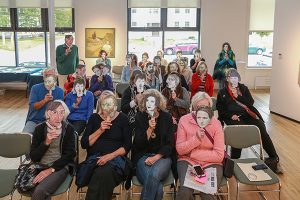 A group of people holding masks of famous artist profiles to their faces