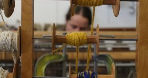 A photograph of artist Britta Fluevog working at her loom