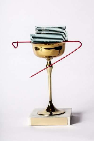 A photograph of a small trophy with a pin and small plates stacked on top of it