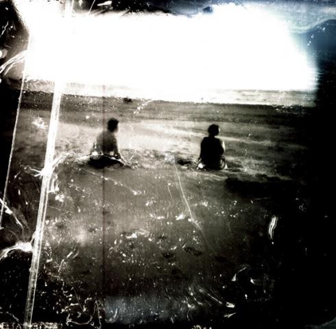 An overexposed photograph o f two boys sitting on a beach