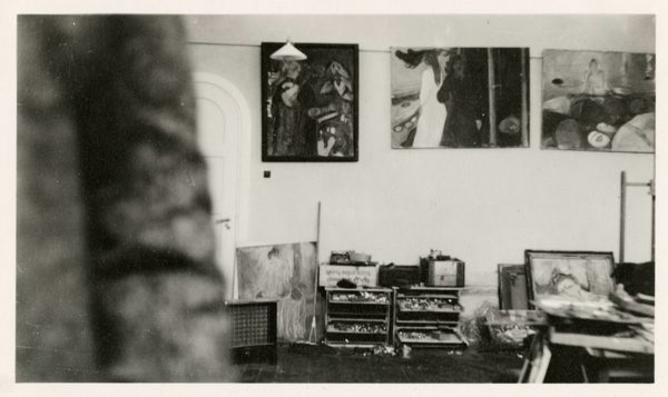 A photograph of an artist in his studio, with only a small section of the artist's torso visible