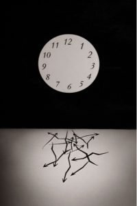 A photograph of an armless clock, with the arms at the bottom of the photograph in a tangle