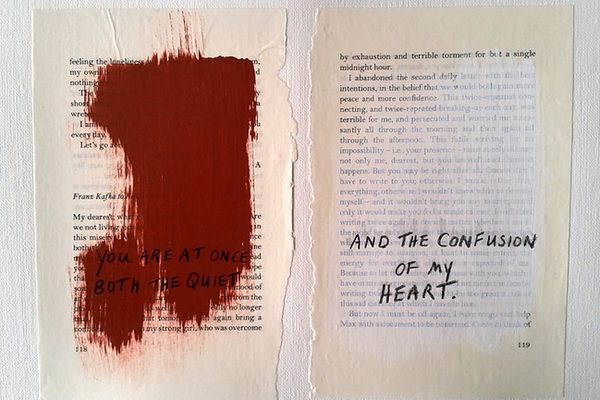 Ripped pages from a book with paint over the text, and new text written over