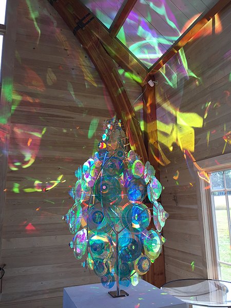 A sculpture covered with film reflects light onto the walls of the barn it is in 