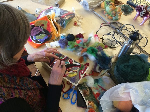 An artist works on a fiber art work in progress