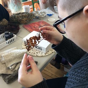 An artist works at a piece of fiber art in progress