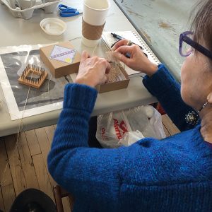 An artist works at a fiber art work in progress