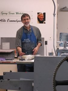 A printmaker works at a press in his studio