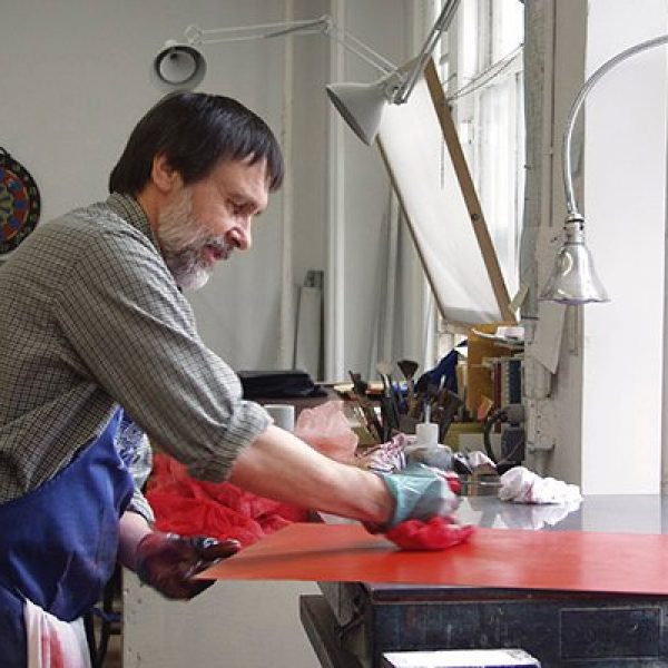 An artist inking a plate in his studio