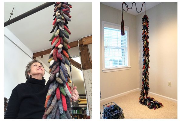 A piece of hanging fiber art with knit "fingers" in hanging form