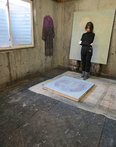 Josie Bell studies a work in progress on the floor of her studio