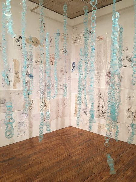 A blue fabric installation hangs from the wall of a gallery