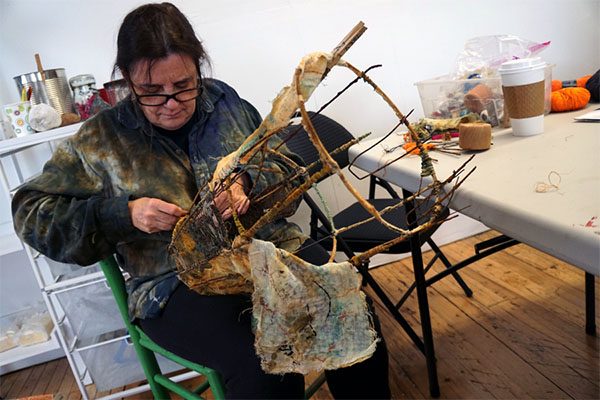 An artist works on a piece of fiber art in progress