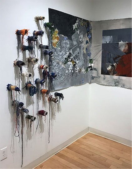 Works of fiber art hang on the wall of a gallery