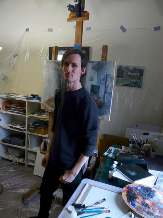 Painter Dillon Samuelson stands in his studio in front of his work