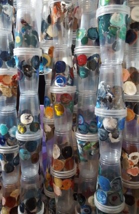 Clear plastic cups filled with clumps of dried paint and tied together