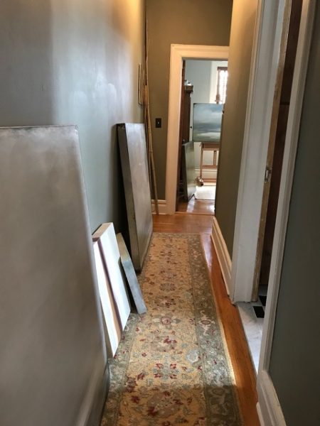 A hallway in an artist's home lined with her paintings