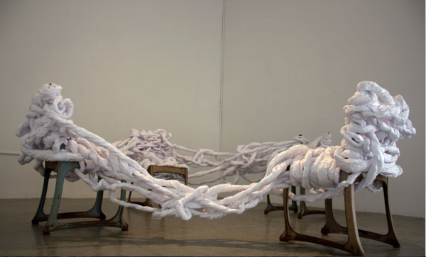 An installation of twisted and woven medical exam papers wrapped around chairs