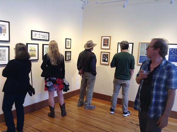 A group of spectators observe art at a gallery exhibition