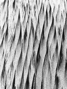 A closeup, black and white picture of sand resembling pointed lines