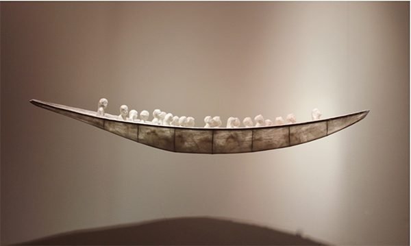 A translucent wooden boat carrying twenty little clay figures representing each child killed in the Sandy Hook school shooting