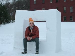 Sculptor Zac Benson sitting on an ice sculpture