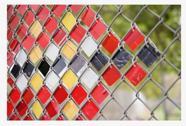 Photographs printed on metal and wired to a chain link fence