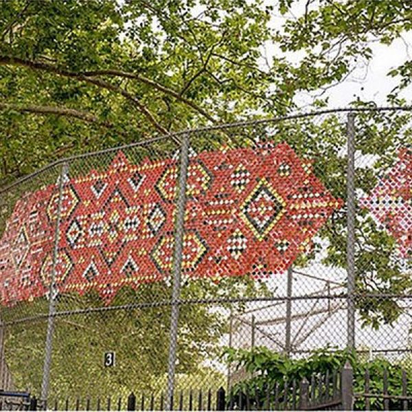 Photographs printed on metal and wired to a chain link fence