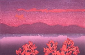 A woodcut of a lake, with trees in the foreground and mountains in the background, at sunset