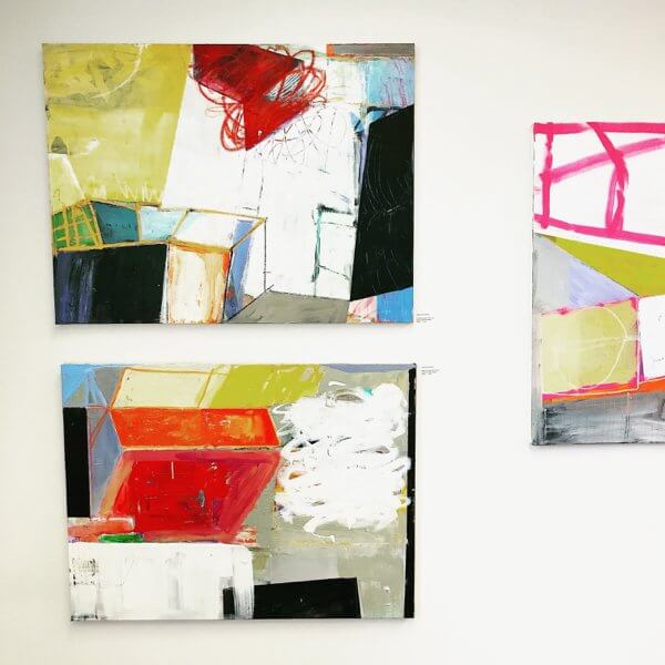 A series of three abstract paintings on a gallery wall