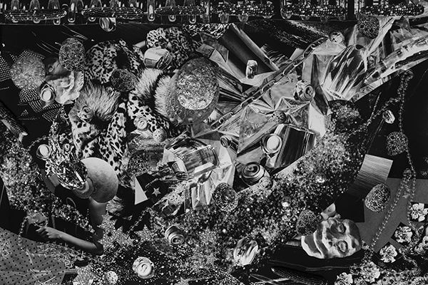 A black and white collage photograph of masks, fabrics, flowers, and more material