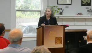 A writer speaking at podium in front of a crowd