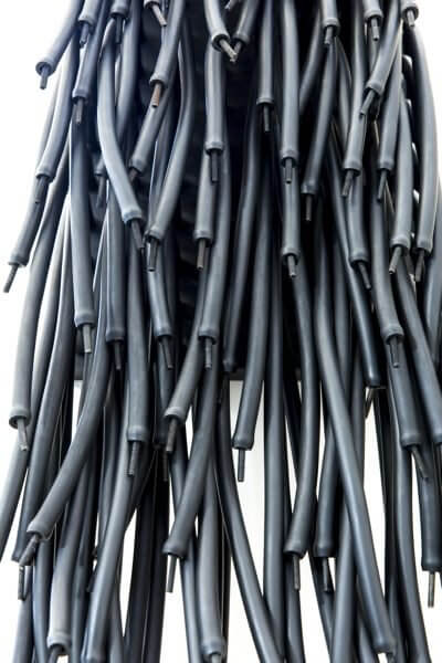 An installation on a wall of hanging black rubber tubing