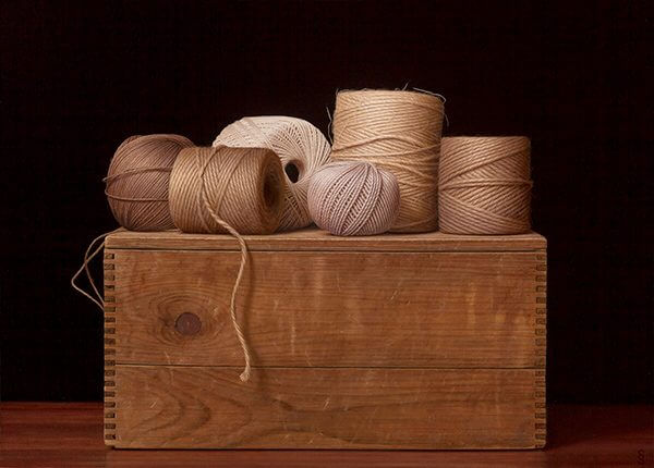 A still life painting of neutral colored spools of thread on a wooden box