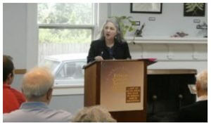 An author at a podium speaking at a seminar