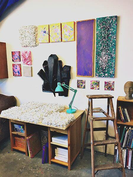 Paintings of crystals and flowers line the wall of an artist's studio