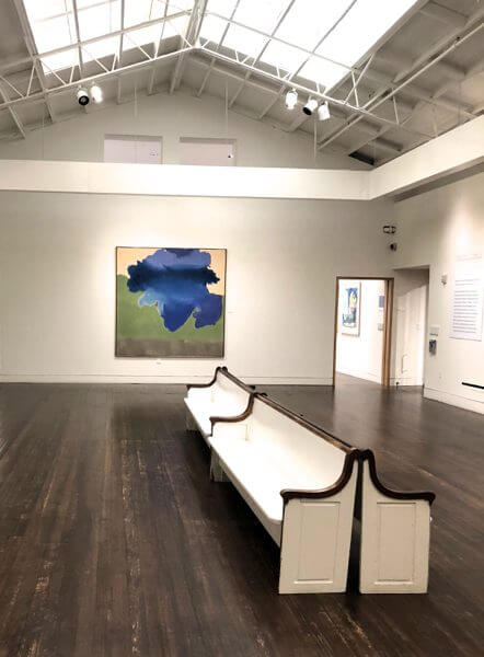 An abstract painting in an art gallery with white walls and benches
