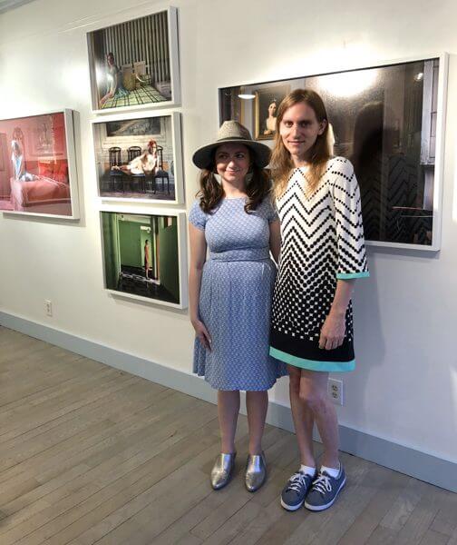 An artist and her muse/model pose in front of their photographs